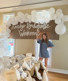 a woman standing in front of a table filled with white balloons