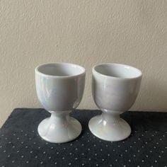 two white cups sitting on top of a table