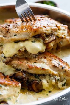 a close up of a plate of food with meat and cheese on it, with a fork in the middle