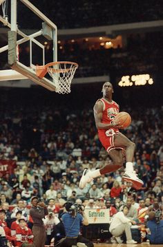 a basketball player jumping up into the air to dunk a ball in front of an audience