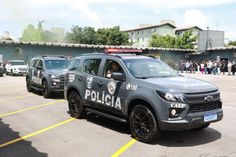 two police cars parked in a parking lot with people standing around the building behind them