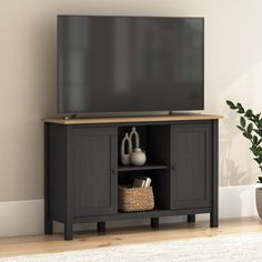 a flat screen tv sitting on top of a wooden entertainment center next to a potted plant