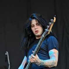 a man with long black hair playing a guitar