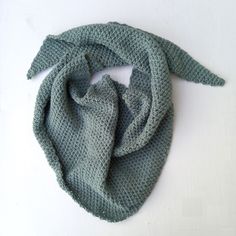 a green knitted scarf sitting on top of a white table