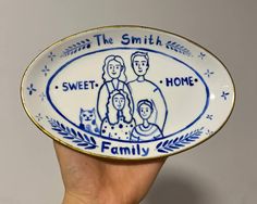 a hand holding a blue and white plate with the words, the smith family on it