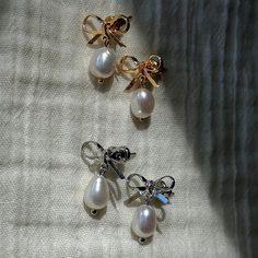 three pairs of earrings with bows on them sitting on a white cloth covered tablecloth