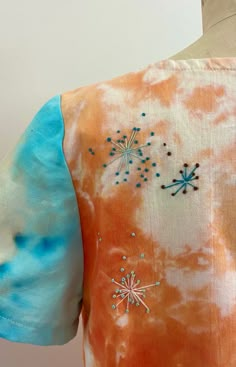 an orange and blue tie dye shirt with stars on the front, back and sides