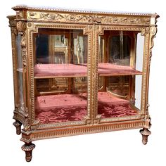 an ornately decorated display case with pink velvet on the bottom and gold trimmings