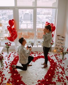 two women sitting on the floor in front of a valentine's day decoration with red heart balloons