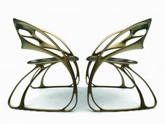 two metal sculptures sitting next to each other on a white surface and one is shaped like a butterfly