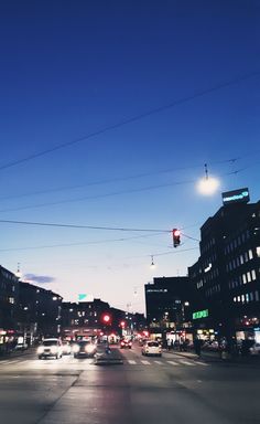 cars are driving down the street at night in front of tall buildings and traffic lights