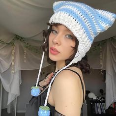 a woman wearing a crocheted hat with blue balls on it