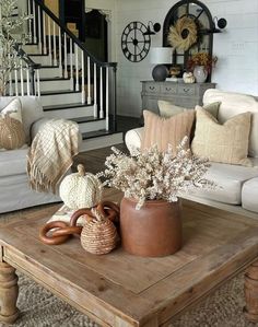 a living room filled with furniture and pillows on top of a wooden table in front of a stair case