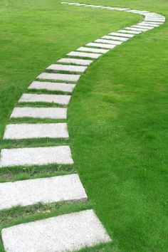 a stone path in the middle of a grassy field