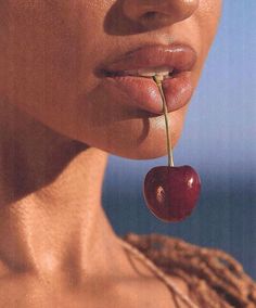 a woman holding a cherry in her mouth