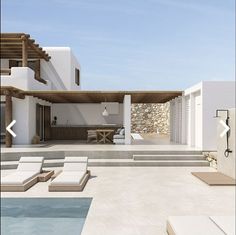 a house with a pool and lounge chairs in front of the swimming pool is surrounded by stone walls