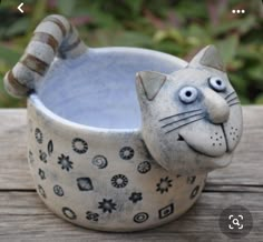 a ceramic cat bowl sitting on top of a wooden table