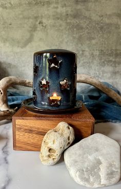 a blue candle sitting on top of a wooden stand next to some rocks and a rock