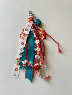 a bunch of different colored beads on a white surface with a red and blue ribbon attached to it