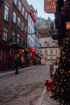 a christmas tree is in the middle of an empty street with buildings on both sides