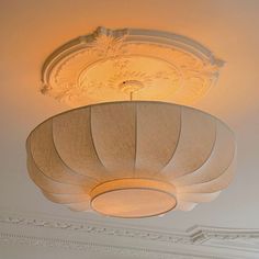 a light fixture in the middle of a room with white walls and trimmings