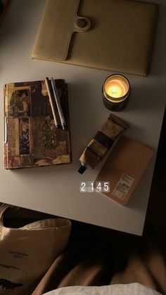 a white table topped with a notebook and a candle next to a bag on top of it