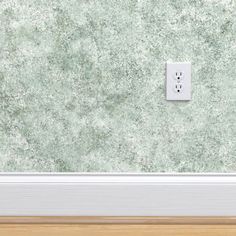 a light switch on the wall in front of a green wallpapered room with wood flooring