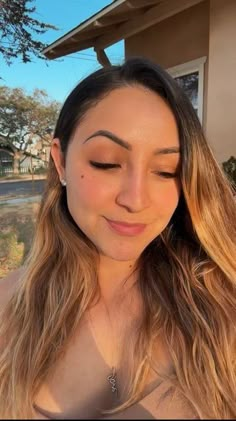 a woman with long brown hair is looking at her cell phone and has eyes closed