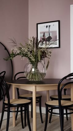 a dining room table with chairs and a vase filled with flowers