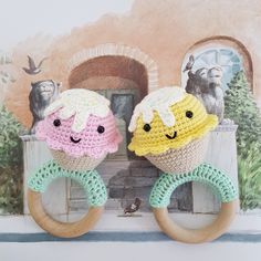 two crocheted rings with faces on them sitting in front of a wall mural