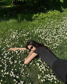 a woman laying on the ground in a field of daisies with her arms stretched out