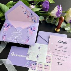 the wedding stationery is laid out with purple flowers and butterflies on it's envelopes