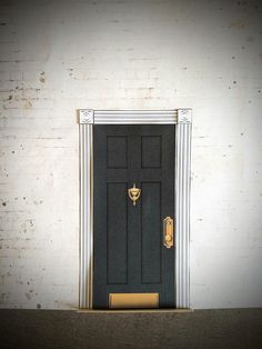 a black door with a gold handle is in front of a white brick wall