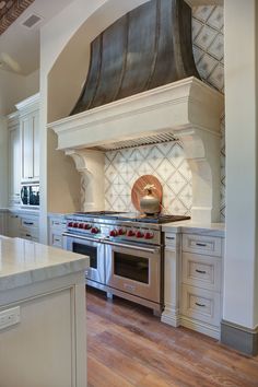 a stove top oven sitting inside of a kitchen next to a wooden floor and white cabinets