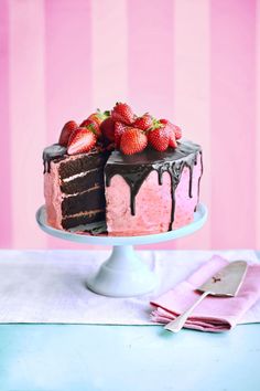 a cake with chocolate icing and strawberries on top is sitting on a table