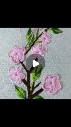 a close up of a flower on a piece of cloth with green leaves and pink flowers