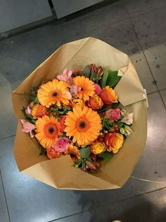 a bouquet of flowers sitting on top of a tiled floor next to a person's foot