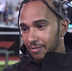 a close up of a person with dreadlocks wearing a black jacket and earrings