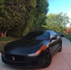 a black masera is parked on the sidewalk