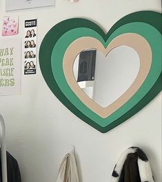 a heart shaped mirror mounted to the side of a wall next to a coat rack