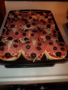 the pizzas are covered in cheese and olives on the stove top, ready to be baked