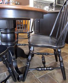 a kitchen table with two chairs next to it on tile flooring and black cabinets