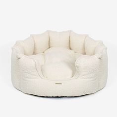 a white dog bed that is made out of fleey material and has a round shaped cushion