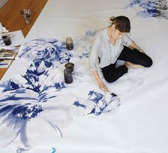 a woman is sitting on the floor working on an art project with watercolors