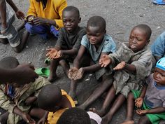 a group of children sitting on the ground with their hands in each other's pockets