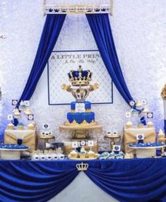 a blue and gold dessert table at a royal baby shower party with cake on top