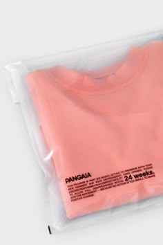 a pink t - shirt in a plastic bag on a white surface with the words pangaia printed on it