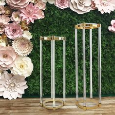 three gold and silver vases sitting in front of a flower wall