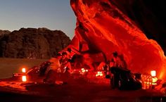 some people are sitting around in the desert at night with candles lit up on them