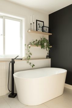 a white bath tub sitting in a bathroom next to a window with plants on it